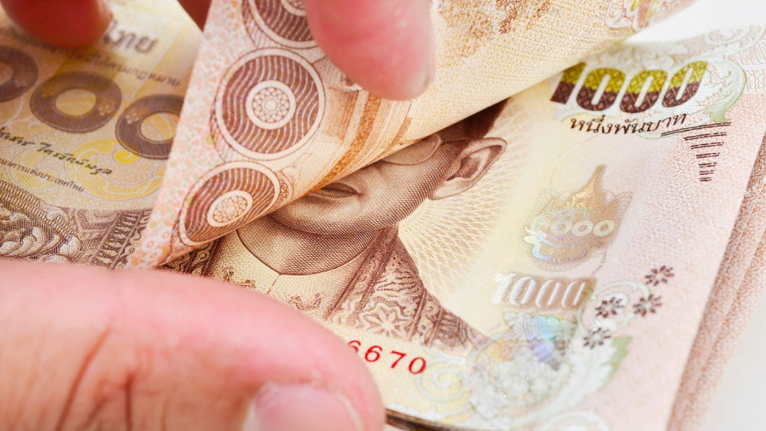 Hands counting 1,000 baht notes.