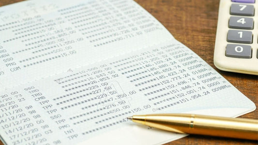 An open Thai bank passbook showing a printed running balance, a pen and calculator beside it.