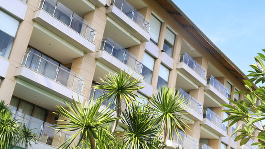 A low-rise Thai condominium block, balconies stacked above the palms at the entrance.