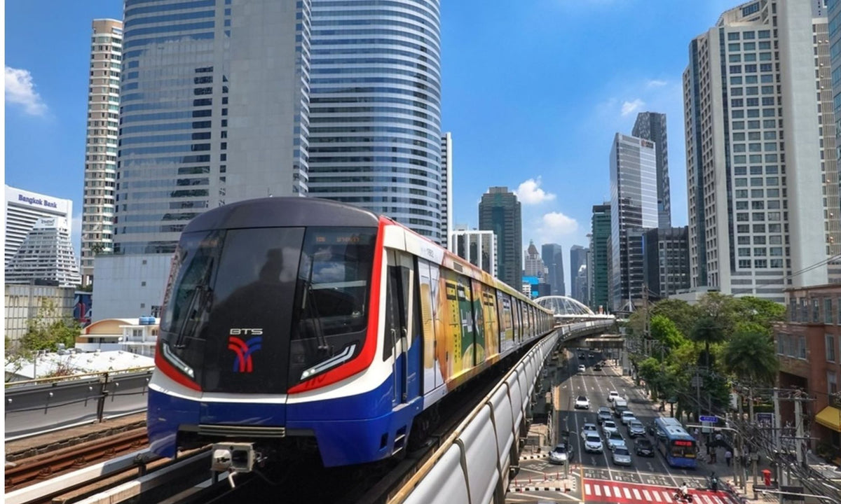 BTS Skytrain running above Sukhumvit Road with the Bangkok skyline behind it